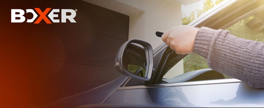Boxer otwieracz do bramy garażowej – osoba otwiera automatyczną bramę garażową pilotem z samochodu