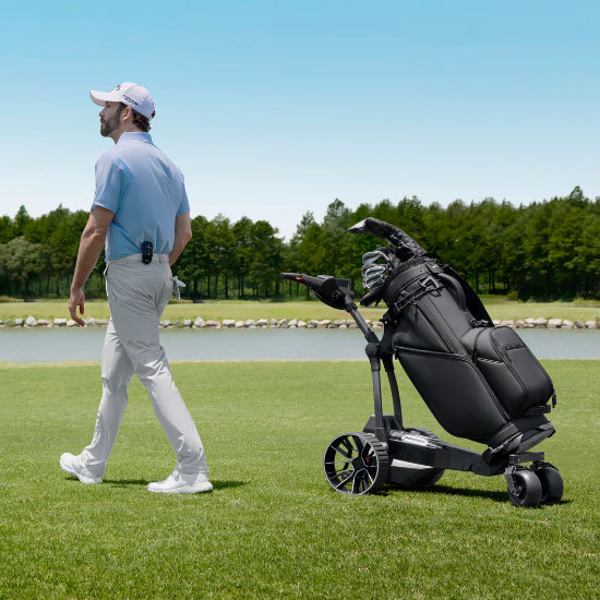 Golfista idzie obok elektrycznego wózka golfowego Navee z torbą golfową na polu golfowym