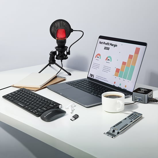 Akcesoria komputerowe Wozinsky z klawiaturą, myszą, mikrofonem, podstawką do laptopa i filiżanką kawy na jasnym biurku