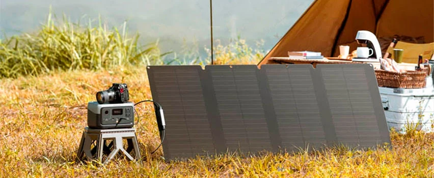 EcoFlow RIVER 2 stacja zasilania i panel słoneczny ustawione przy namiocie na łące – kompaktowe rozwiązanie off-grid do campingu