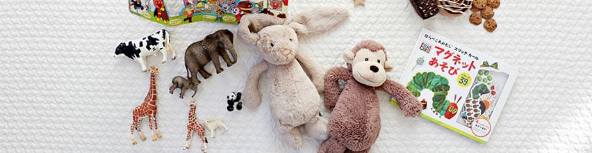 Baby sitter på et teppe fullt av leker og bøker.